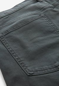 Tăietură din denim gri închis, cu un buzunar din spate cu cusături vizibile și o suprafață texturată, prezentând un model diagonal de nervuri.