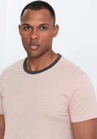 Lyserød t-shirt med korte ærmer, kontrasterende mørkegrå ribbede halsudskæring, afslappet pasform og blød tekstur.