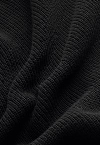 Fekete, textúrált anyag bordázott mintával, amely puha, szőtt szálakat mutat be, létrehozva mélységet és dimenziót.