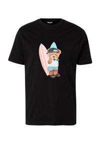 T-shirt noir avec un ours en peluche portant une casquette, des lunettes de soleil, un short et des sandales, debout devant deux planches de surf.