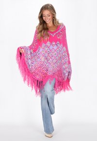 Heldere roze poncho met diamantpatronen in paars en geel. Beschikt over lange franjes aan de onderrand en een open ontwerp. Zachte, gestructureerde stof.