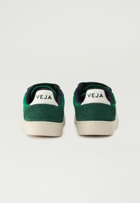 Zelené semišové tenisky s bílým patním dílem, vykazující embosované logo 'VEJA', námořnický vnitřek a béžovou gumovou podrážku.