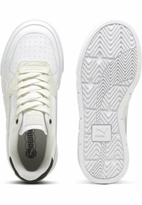 Baskets blanches avec un dessus en cuir texturé, bout rond et lacets plats. La semelle présente un motif ondulé et un accent noir au niveau du talon.