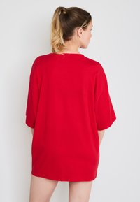 Czerwona, oversize, bawełniana koszulka z okrągłym dekoltem i krótkimi rękawami. Gładka tekstura z prostym dołem.