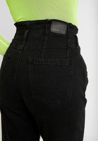 Hoge taille zwarte denim jeans met een gestructureerde afwerking, voorzien van een achterzak en een leren patch met merknaam op de tailleband.