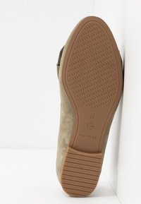 Chaussure en daim vert olive avec une semelle en caoutchouc texturé. La semelle présente une adhérence à motif, marquée de la taille 37 et de la marque "tamaris".