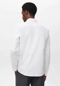 Camicia bianca a maniche lunghe, con colletto classico, orlo dritto sul retro e polsini a contrasto, realizzata in tessuto morbido.