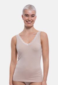Light beige tank top with a V-neckline, featuring delicate white lace trim along the edge. Made from soft, stretchable fabric.
