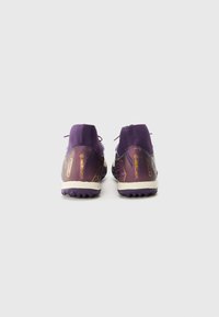Baskets de sport violettes avec une surface texturée, dotées d'un talon bas, d'une semelle contrastante claire et d'une marque notable sur les côtés.