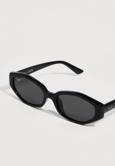 Черни слънчеви очила Ray-Ban с гладки, леко правоъгълни стъкла и тънки дръжки, показани под ъгъл на светлосив фон.