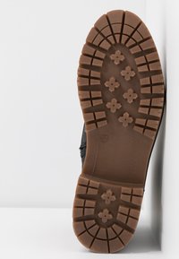 Semelle de botte avec un motif de bande de roulement profond comportant des crampons rectangulaires et en forme de fleur en caoutchouc marron, taille 37 marquée.