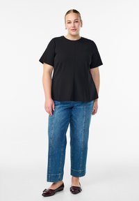 Juodas trumpomis rankovėmis vartymas su apvaliu iškirpimu, derinamas su šviesiai mėlynomis aukšto liemens džinsomis ir tamsiai burgundiškomis butais su dekoratyviniais akcentais.