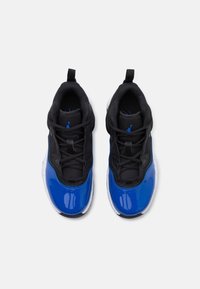 Atletické tenisky s černým síťovaným svrškem a lesklými modrými lakovanými koženými akcenty. Bílá gumová podrážka s černým protiprokluzovým vzorem. Bezšňůrový design, pohled shora.