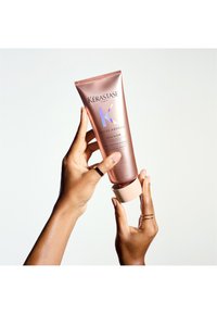 Kérastase Gloss Absolu, een roségouden tube met een matte afwerking en een perzikkleurige dop, heeft holografische letters en een slank, modern ontwerp.