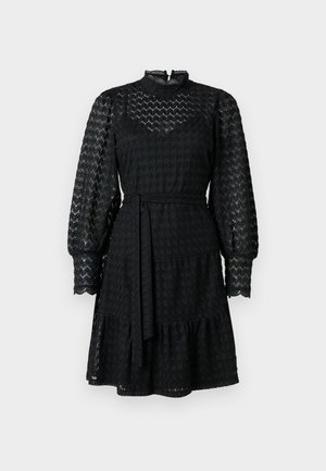 Abito in pizzo nero con maniche lunghe a sbuffo, colletto alto, gonna a strati e cintura. Presenta un motivo scallop e un tessuto testurizzato.