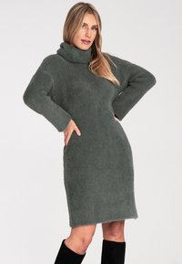 Graues, flauschiges Strickkleid mit hochgezogener Kapuze, langen Ärmeln und einer leicht taillierten Silhouette, das eine weiche Textur und einen knielangen Saum aufweist.