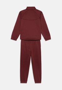 Μπορντό φόρεμα γυμναστικής που περιλαμβάνει μια ζακέτα με φερμουάρ και όρθιο γιακά, συνδυασμένη με παντελόνι με ελαστική μέση και μανσέτες.