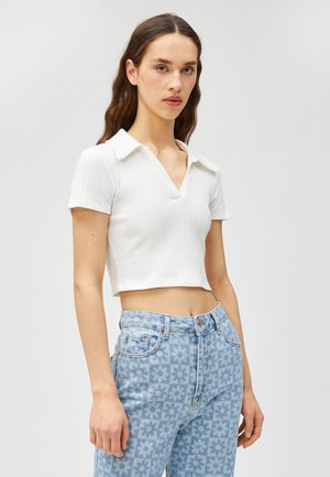 Vit ribbad crop-top med krage och korta ärmar, i kombination med ljusblå jeans med blommönster och hög midja.
