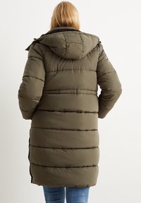 Grøn pufferjakke med hætte, der har vandrette quiltede sektioner, elastiske manchetter og en lang kant. Blød tekstur og varm isolering.