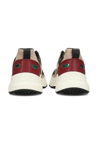 Un paio di sneaker beige, nere e rosse con suole bianche, viste da dietro, con dettagli verdi e linguette nere.