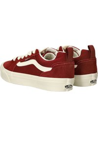 Zapatillas de ante rojo con acentos blancos, que presentan una puntera redondeada, suelas gruesas de color crema y una pestaña trasera con detalle del logo.