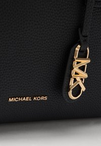 Zwarte leren handtas met een gestructureerde afwerking, voorzien van gouden hardware en een logo-label. Gegraveerd "MICHAEL KORS" in goud aan de voorkant.