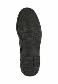 Black rubber shoe sole with textured grip, featuring circular and oval patterns. Designed for traction with a contoured shape.