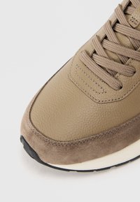 Sneakers em couro e camurça bege com parte superior texturizada, atacadores planos e sola de borracha. Biqueira arredondada e detalhes cosidos nas bordas.