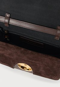 Offene dunkelbraune Handtasche aus Wildleder und Leder mit schwarzem Innenfutter, Reißverschlusstasche und goldfarbenem Metallverschluss.