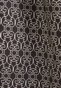 Tissu noir avec un motif répétitif de lignes courbes abstraites blanches interconnectées et de formes circulaires.