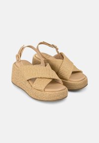Sandali con zeppa in paglia intrecciata di colore beige chiaro, con design a cinturino incrociato e fibbia regolabile alla caviglia. Suola liscia.