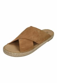 Tan suede slide sandal with crossed straps, flat jute sole, and visible stitching along the edges. Interior has a smooth finish.