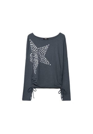 Dunkelgraues Langarmoberteil mit einem großen silbernen Stern aus runden Nieten auf der Vorderseite und Kordelzügen am Saum.
