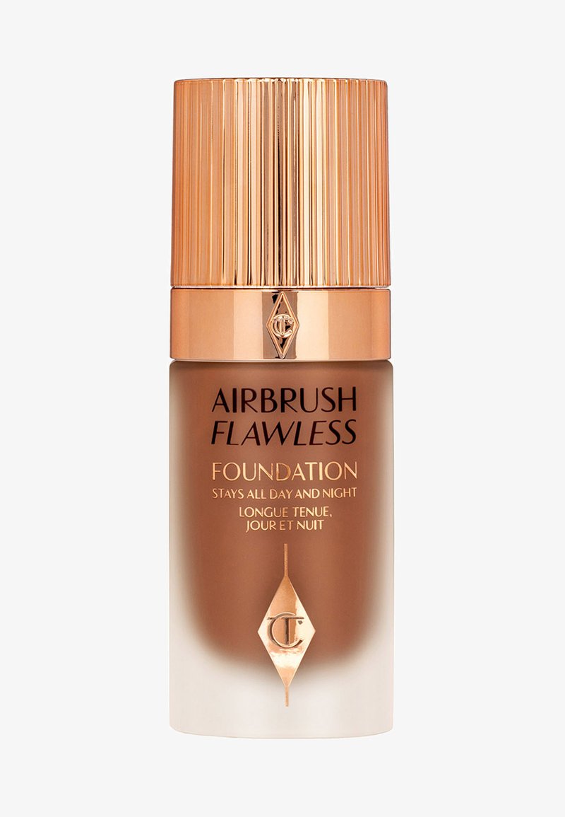 Airbrush Flawless Foundation in einer klaren Glasflasche mit einem goldenen gerippten Deckel. Besitzt goldene Akzente und schwarze Schrift auf einem beige-gefärbten Hintergrund.