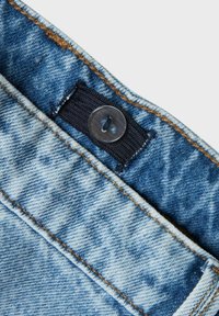 Tessuto di denim, azzurro chiaro con una texture consumata. Presenta un pulsante nero e un anello di stoffa nella parte superiore, con cuciture marroni a contrasto.