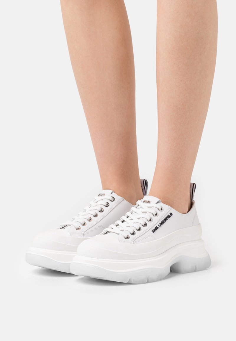 Baskets à plateforme blanches avec une tige en cuir lisse. Dotées d'œillets métalliques, d'une semelle épaisse et d'un détail de logo sur le côté et la languette du talon.