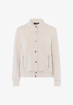 Hellbeige Jacke mit Stehkragen, vorderer Druckknopfleiste und seitlichen Reißverschlusstaschen. Sie hat eine glatte Textur und kontrastierende weiße Nähte.
