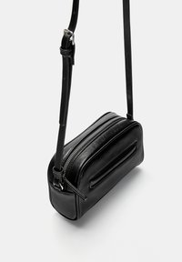 Svart läder crossbody-väska med rektangulär form, enkel dragkedjestängning och justerbar rem; har en sidoficka med dragkedja och slät yta.