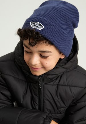 Beanie blu lavorato a maglia con etichetta tessuta, giacca imbottita nera con chiusura a zip e logo, evidenziando la trama a coste e la vestibilità aderente.