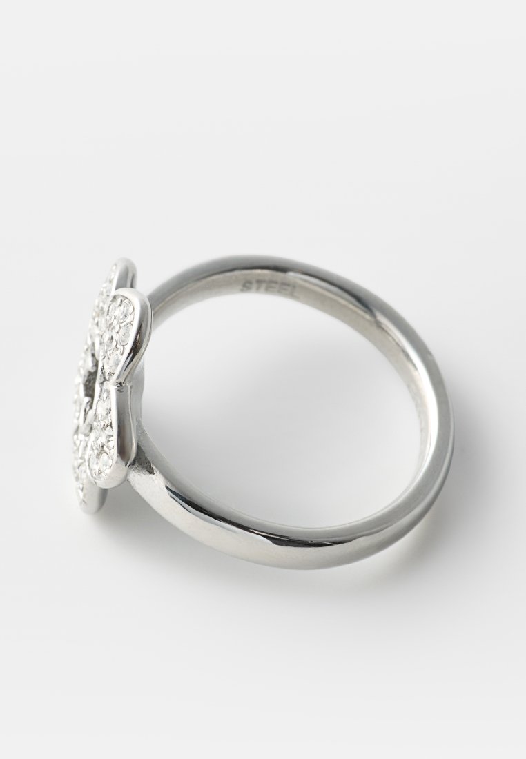 Anillo de metal plateado con un diseño en forma de flor en la parte superior incrustado con pequeños cristales transparentes.