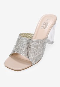 Sandalia de tacón mule con punta abierta y tacón de bloque transparente, que presenta una ancha banda adornada con cristales de plata y una plantilla de cuero en color nude.