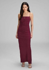 Burgunderfarbendes Maxikleid mit dünnen Trägern, gerafftem Stoff, taillierter Silhouette und geradem Saum. Getragen mit silbernen offenen Sandalen.