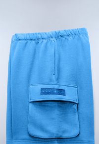 Lichtblauwe sweatpants met een elastische tailleband en een grote voorzak met klep voorzien van een Napapijri-logo patch.