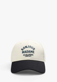 Baseballpet met een beige katoenen lichaam en een zwarte klep. Voorzien van geborduurde tekst "BONJOUR MADAME" en "SCALPERS COMPANY" in het blauw.