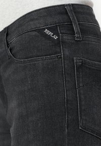 Jeans negre din denim cu un design ajustat, dotate cu un eticheta logo cusut distinctivă, cinci buzunare și o textură subtilă.