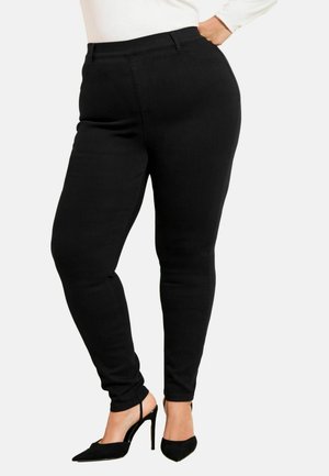 Pantaloni negri mulati dintr-un material elastic, cu croială ajustată, buzunare laterale și talie medie, asortați cu pantofi cu toc înalt negri.