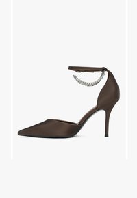 Brown satin high-heeled shoe with a pointed toe and an ankle strap featuring a row of clear rhinestones. Sleek design with a slender heel.
