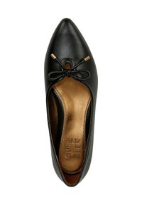 Scarpa piatta in pelle nera con punta appuntita, caratterizzata da un fiocco decorativo, accenti dorati e una texture liscia e lucida con una soletta marrone.