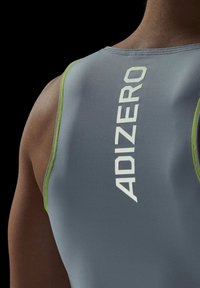 Grå atletisk tanktop med tætsiddende pasform, grønne accenter langs kanterne og "ADIZERO" branding i hvid på ryggen.