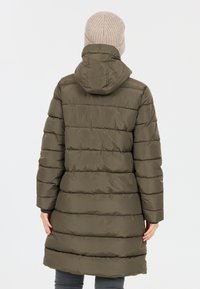 Cappotto imbottito verde oliva con cuciture orizzontali, cappuccio e maniche lunghe. Indossato oversize, arriva a metà coscia, abbinato a un cappello di maglia beige.